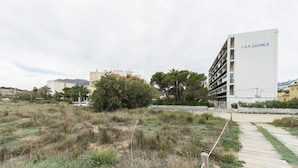 A building named 'Les Gavines' with a modern design, surrounded by a natural landscape with a wooden pathway leading to it. - LES GAVINES - Charming apartment with sea views - Free Wifi (Dénia)