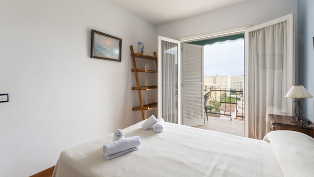A hotel room with a bed, a wooden ladder, a balcony with a view, and a painting on the wall. - LES GAVINES - Charming apartment with sea views - Free Wifi (Dénia)