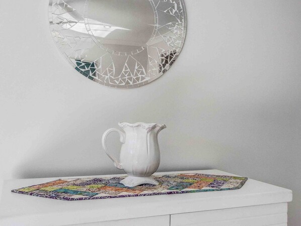 Een witte tafel met een decoratieve karaf en een kleurrijke placemat.