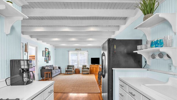 A modern kitchen with white cabinetry, a black refrigerator, and a coffee machine.