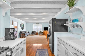 Una cocina moderna con armarios blancos, un refrigerador negro y una cafetera.