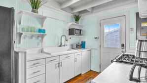 A kitchen with white cabinetry, a stainless steel stove, a microwave, and a sink.