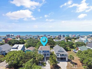 A coastal residential area with houses, a clear sky, and a view of the ocean.