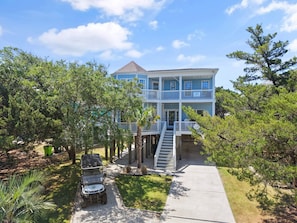 A two-story building with a balcony, a covered porch, and a pathway leading to the entrance.