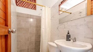 A bathroom with a toilet, sink, and shower curtain. - Hotel talu  tayrona (Santa Marta)