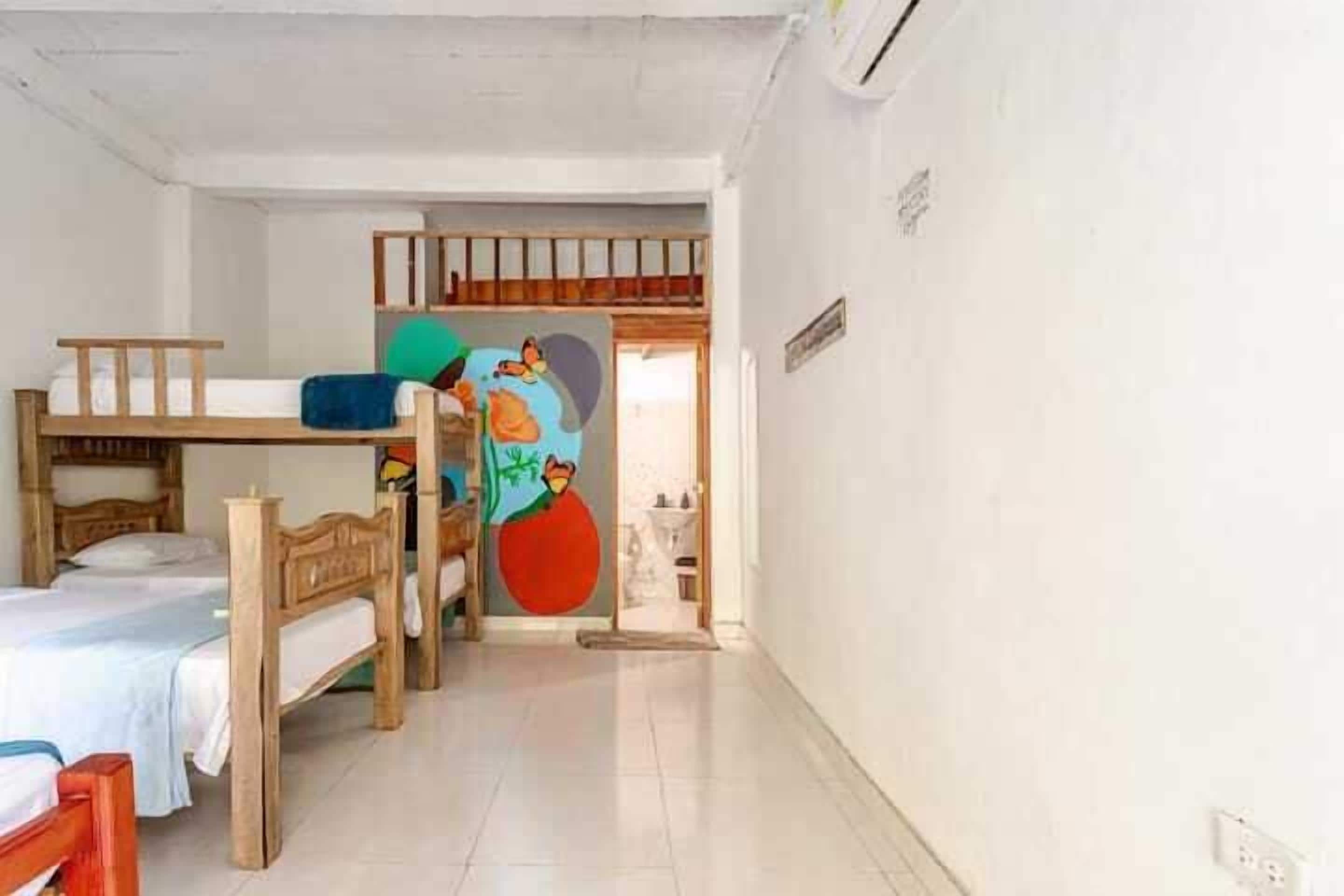 A room with bunk beds, a colorful mural, and a tiled floor.