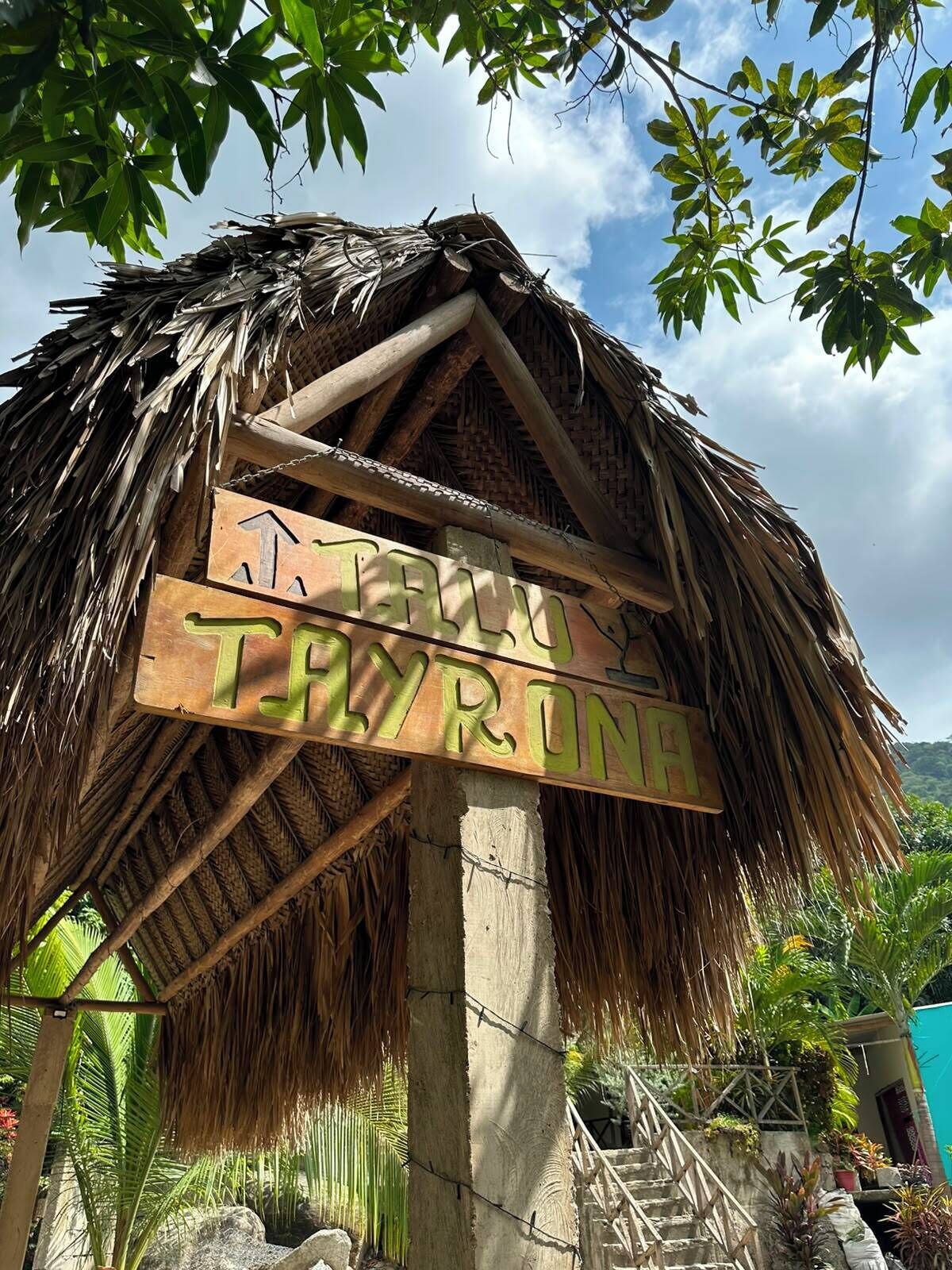 A thatched roof structure with a wooden sign reading 'TRAVEL THRONE.'