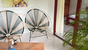A room with two wicker chairs, a wooden table, and a painting on the wall. - Hotel talu  tayrona (Santa Marta)