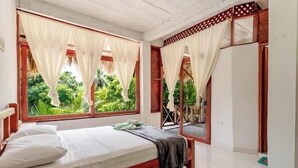 A bedroom with a bed, curtains, and a view of greenery outside. - Hotel talu  tayrona (Santa Marta)