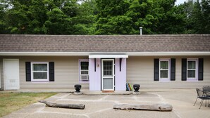 Un motel à deux étages, à la façade beige, aux fenêtres encadrées de pourpre et doté d’un porche avec un banc.