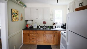 Une cuisine avec des meubles blancs, un plan de travail noir et un réfrigérateur blanc.