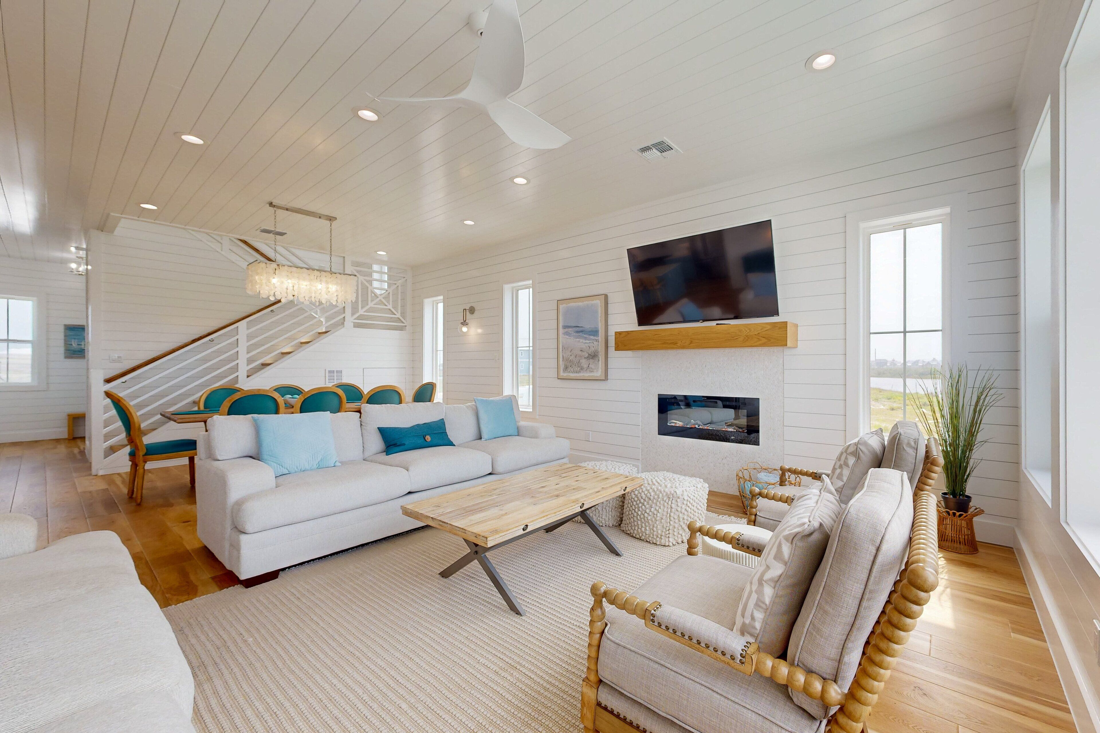 A spacious living room with a wooden coffee table, white sofas, and a staircase leading to an upper level.