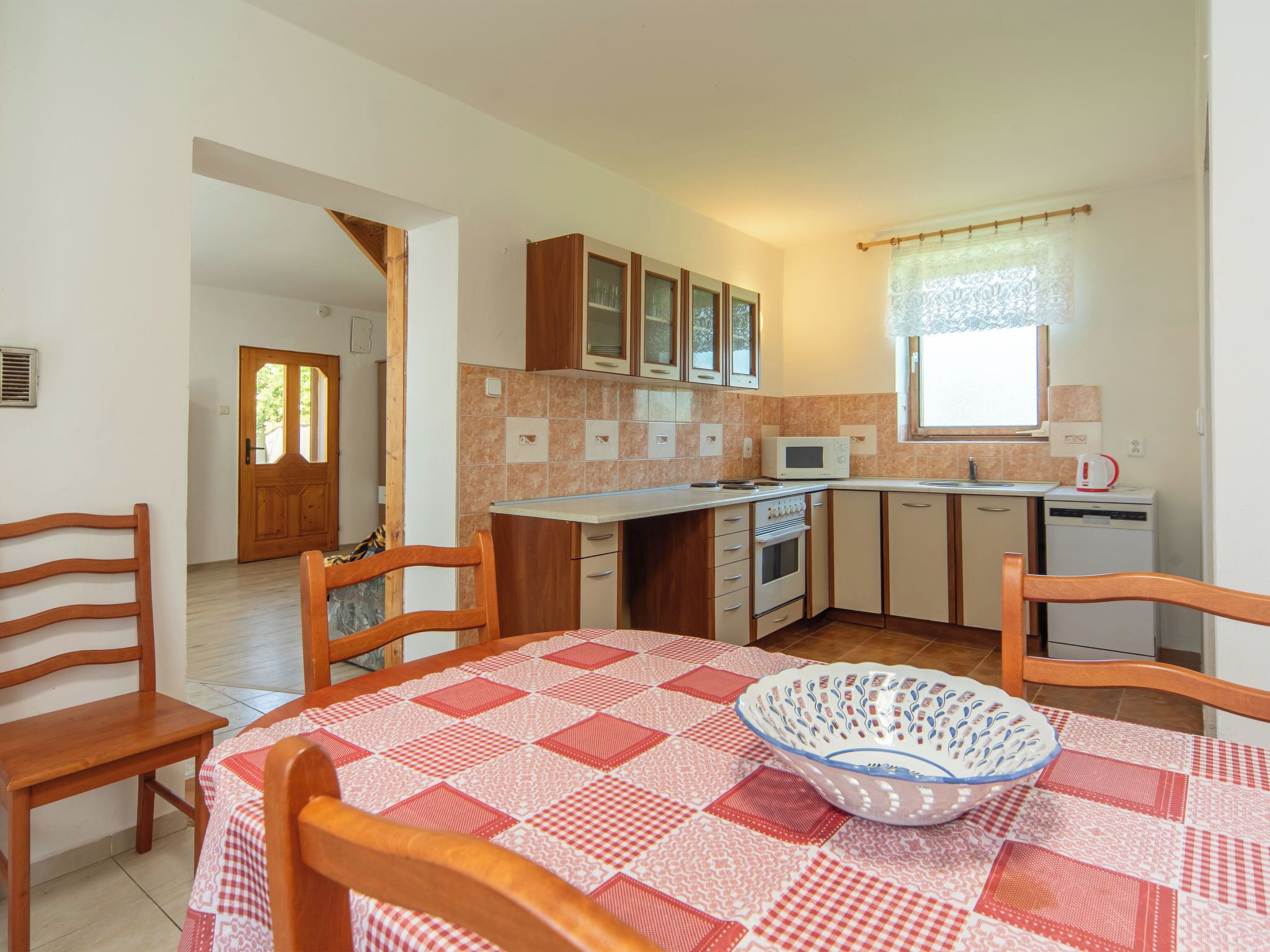 Una cocina compacta con armarios de madera, un microondas y un lavamanos.