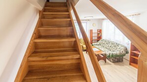A wooden staircase leading to a loft bedroom with a view of the outside.