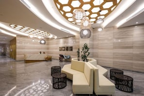 A modern lobby with a reception desk, seating area, and decorative lighting. - Sentral Suites KL Sentral By Luxe Home (Kuala Lumpur)