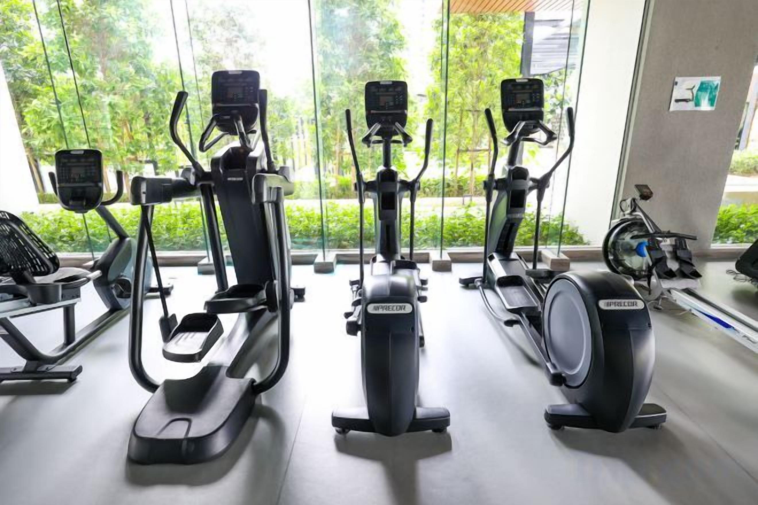 Et fitnessrum med motionscykler, løbebånd og en motionscykel med digital skærm.