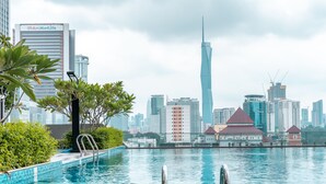 A swimming pool with a city skyline in the background, including a tall skyscraper. - Sentral Suites (Kuala Lumpur)