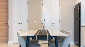 A modern kitchen with a dining table, chairs, and a refrigerator. - Sentral Suites (Kuala Lumpur)