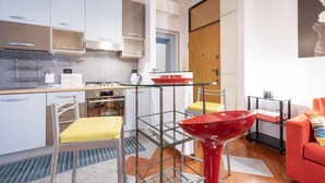 A modern kitchen with white cabinets, stainless steel appliances, and a glass table. - Italianway Easy - Masotto 4 (Milan)