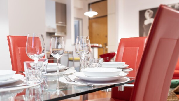 A dining table set with white plates, clear glasses, and red chairs. - Italianway Easy - Masotto 4 (Milan)