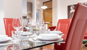 A dining table set with white plates, clear glasses, and red chairs. - Italianway Easy - Masotto 4 (Milan)