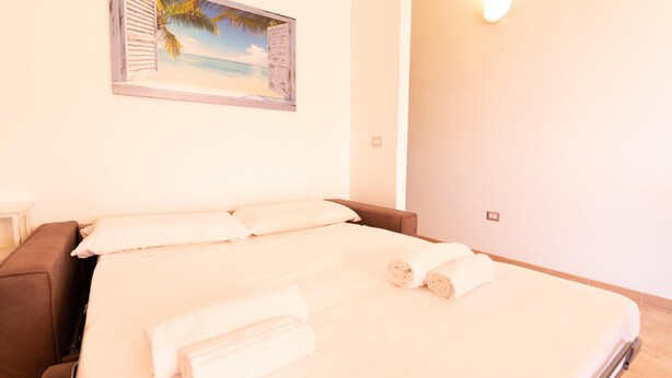 Un dormitorio con cama, almohadas y un cuadro de una playa.