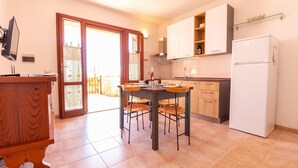 Una cocina con una mesa de comedor, sillas, un refrigerador y armarios.