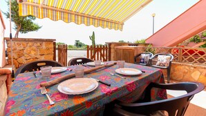 Una mesa preparada para dos con mantel colorido, platos, cubiertos y una copa.