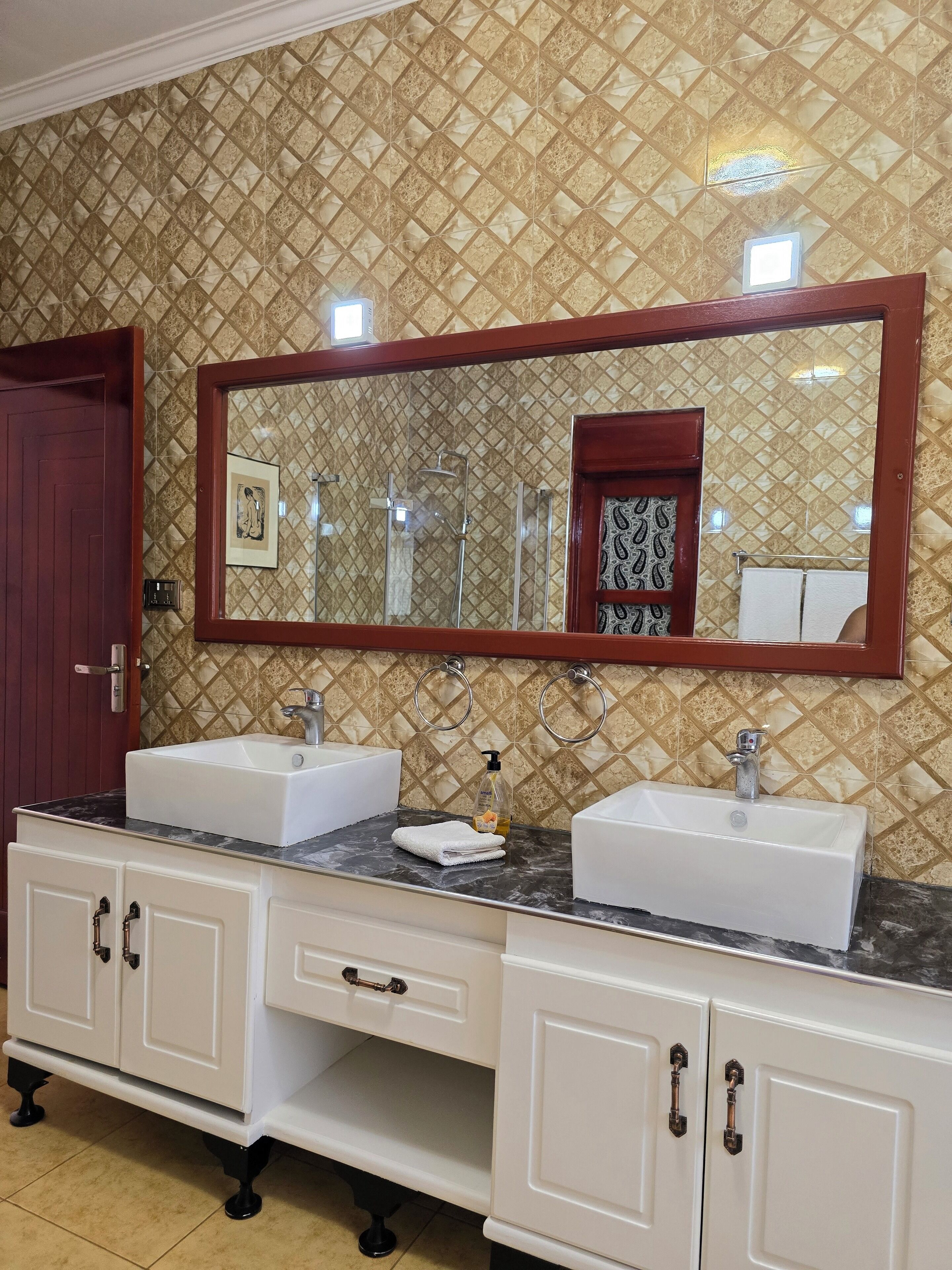 Uma casa de banho com duas pias, um espelho grande e uma cómoda com armários.