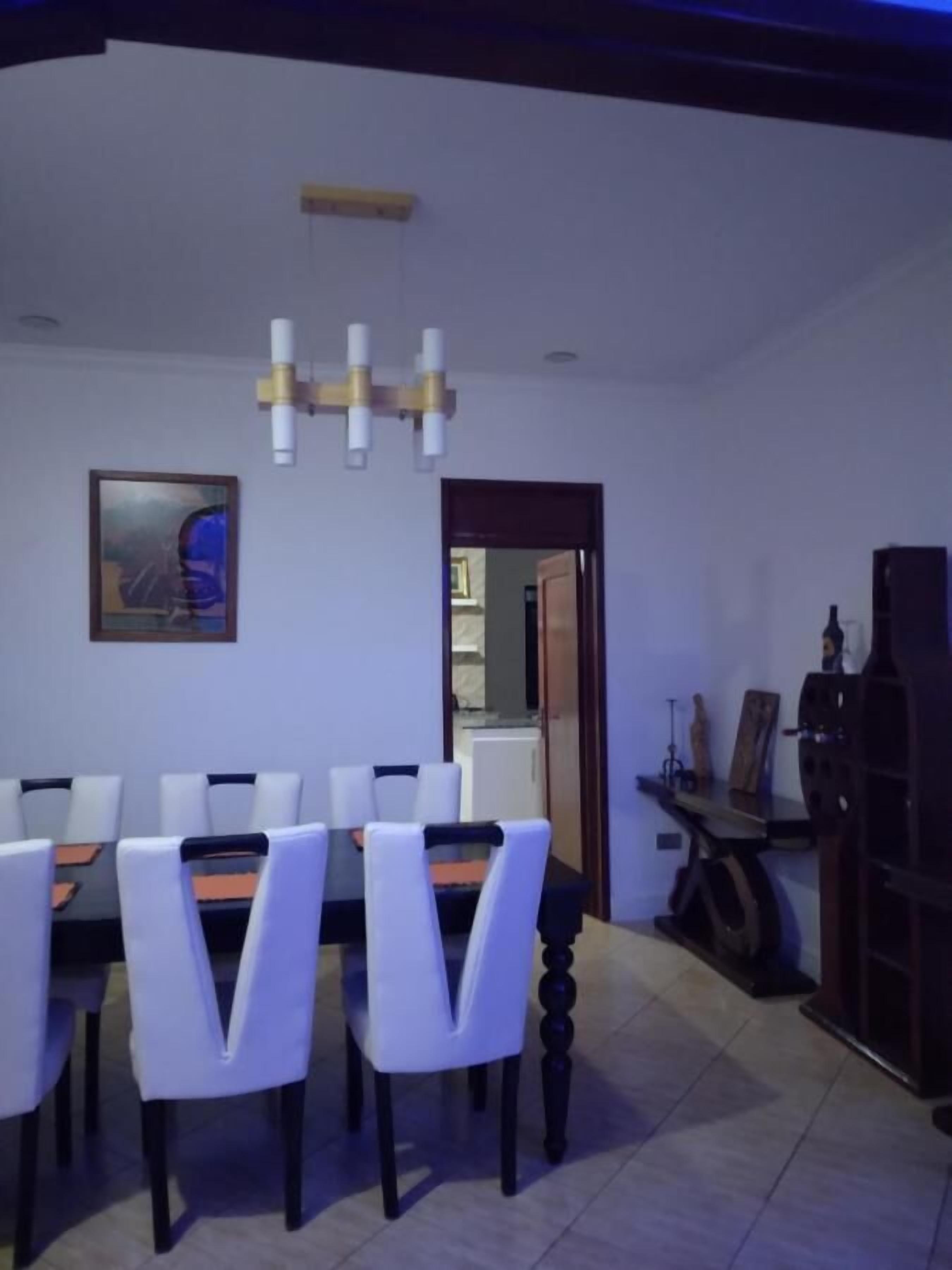 A dining area with a table and chairs, a painting on the wall, and a door leading to another room.