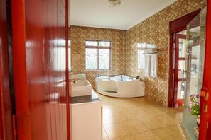 A bathroom with a bathtub, a sink, and a window. - Sprunger Avenue-Tulia Homes  (Moshi)
