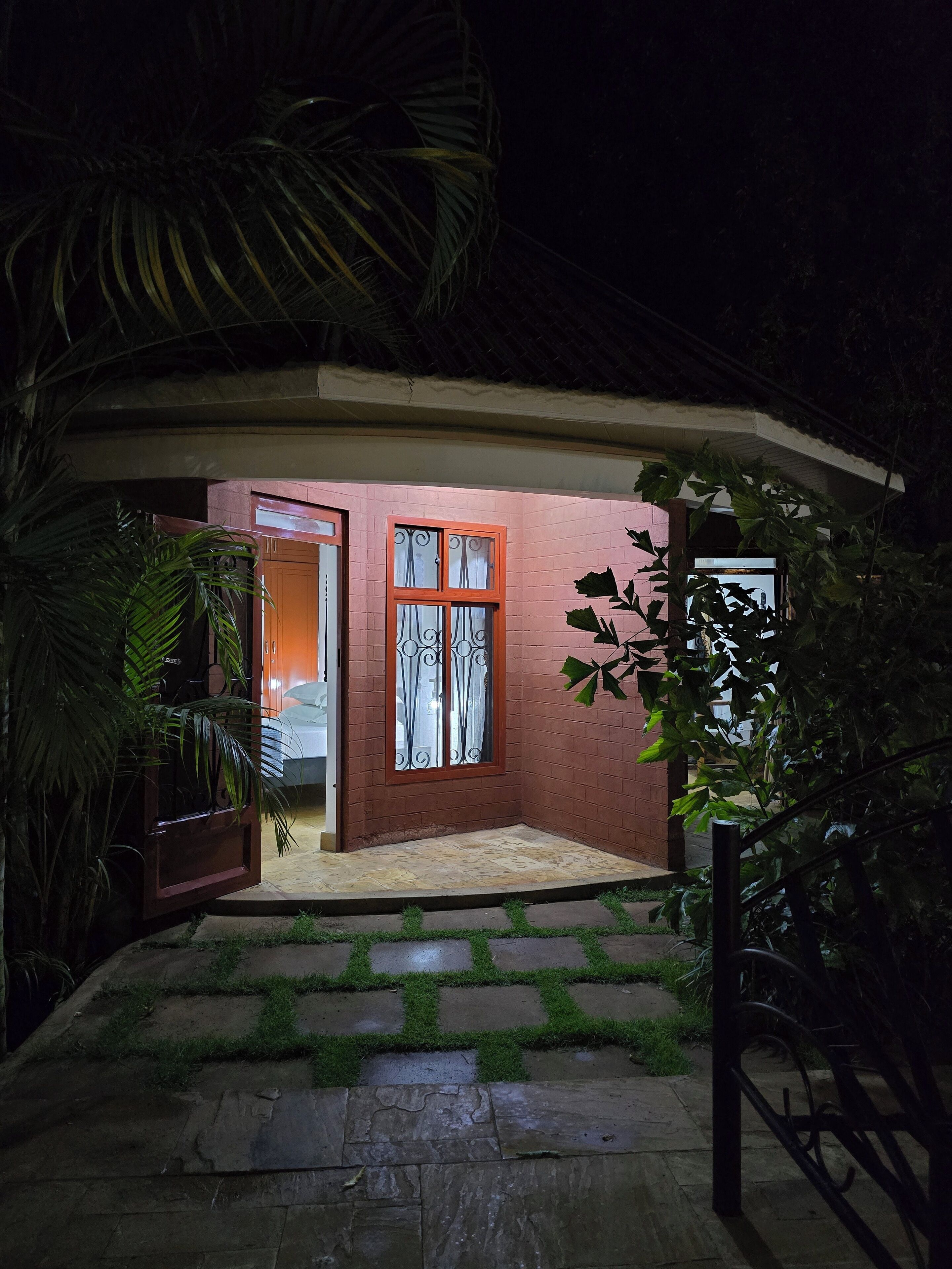 Ein Haus mit roter Ziegelstein-Fassade, einer Glastür und einem Fenster mit schmiedeeisernen Gitterstäben.