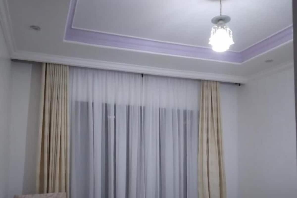 A hotel room with a bed, a chair, a small table, and curtains.