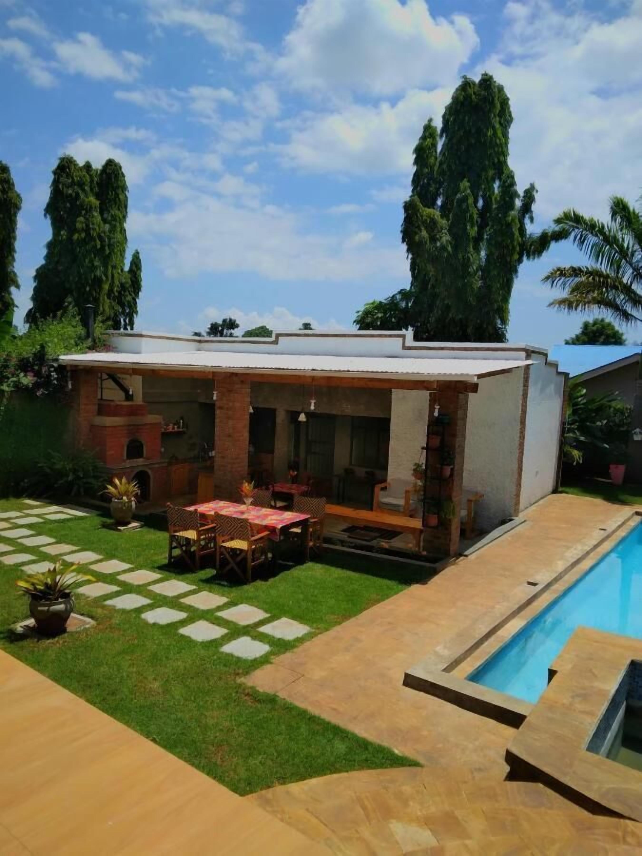 A house with a covered patio, a swimming pool, and a well-maintained lawn.