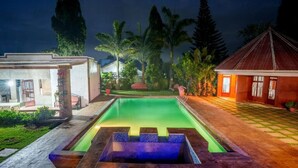 A swimming pool with a wooden deck and a small waterfall feature. - Sprunger Avenue-Tulia Homes  (Moshi)
