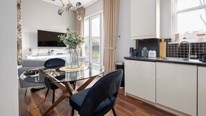 A modern kitchen with a dining area, a TV, and a view of the outdoors. - GuestReady - Fabulous stay in Fulham (London)