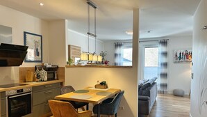 Een moderne keuken met een eethoek, houten vloeren en een bank in de woonkamer.