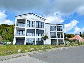 Un moderno edificio residencial de varios pisos con balcones, ventanas amplias y techo plano.