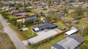 An aerial view of a residential area with houses, green spaces, and a road.