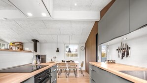 A modern kitchen with a central island, grey cabinetry, and a wooden countertop.