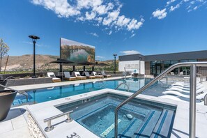 Une piscine avec des chaises longues et des parasols, une grande fresque murale et un bâtiment en arrière-plan.