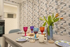Una mesa de comedor con platos, vasos y un jarrón de flores.