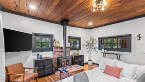 A cozy bedroom with a fireplace, wooden flooring, a bed with white bedding, and a modern chair.