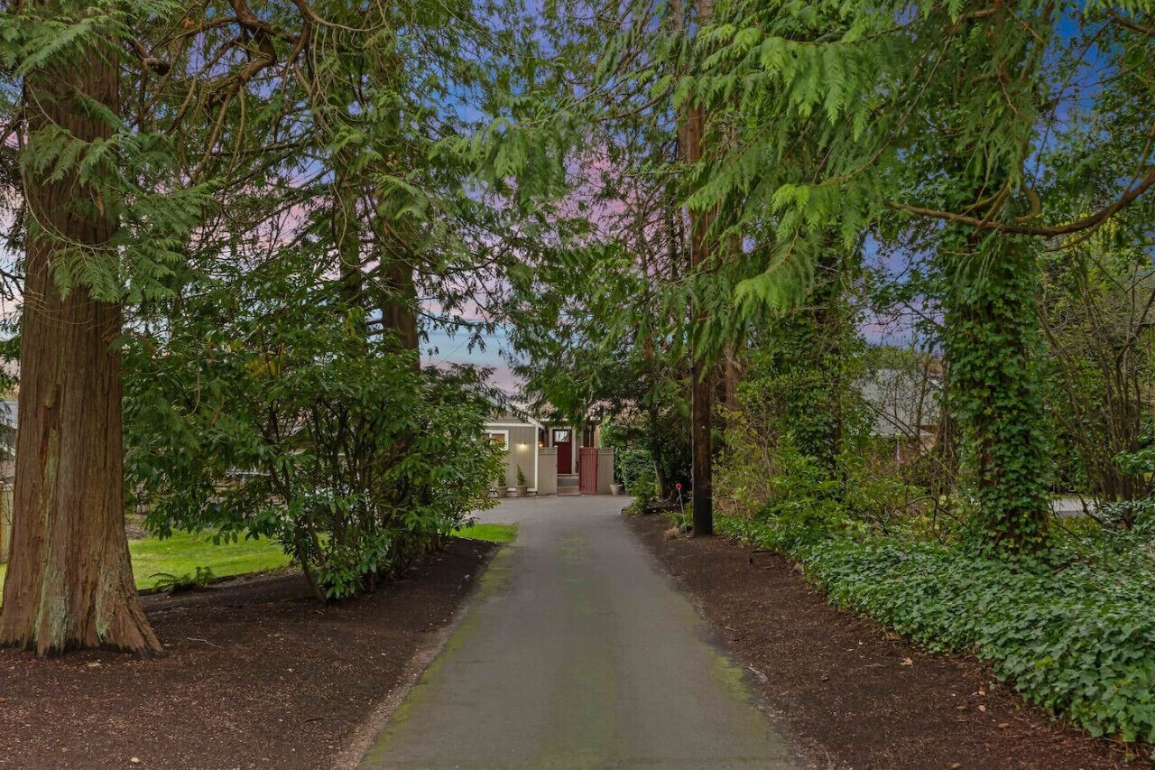 Un chemin bordé d’arbres mène à un bâtiment dont la porte est rouge.