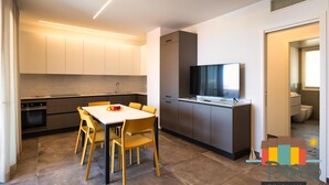 Una cucina moderna con zona pranzo, elettrodomestici integrati e una televisione a schermo piatto.