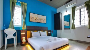 A modern hotel room with a large bed, a chair, a painting, and a ceiling fan. - Sarvam Serviced Apartment (Coimbatore)
