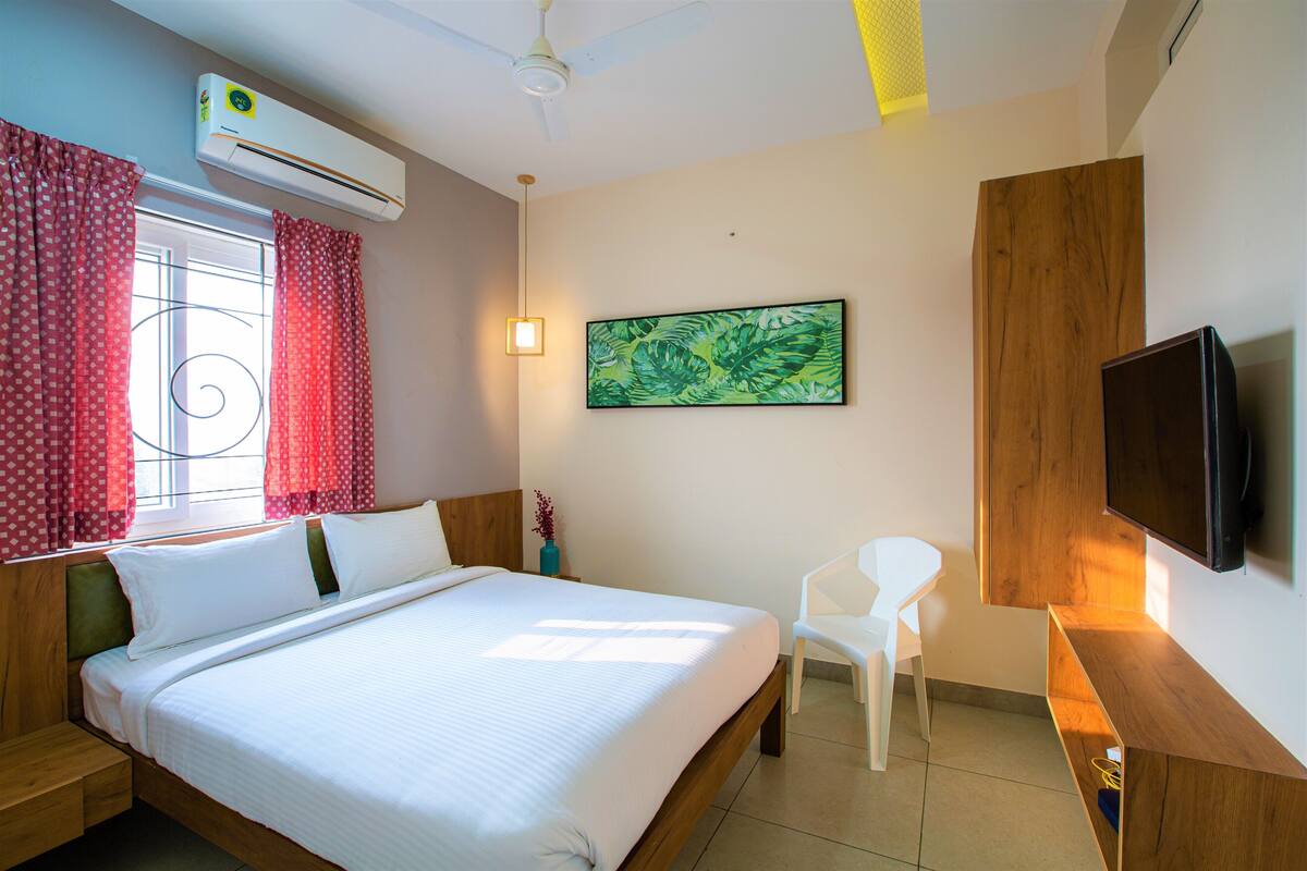A hotel room with a bed, a TV, a desk, and a chair.