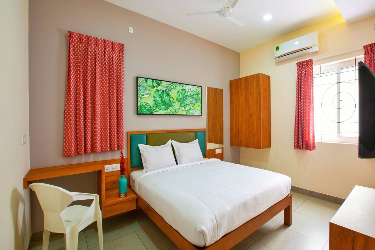 A bedroom with a bed, a desk, a chair, a ceiling fan, and an air conditioning unit.