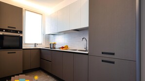 A modern kitchen with grey cabinets, a built-in oven, a window, and a sink. - Fantastic new penthouse with seaview P 21 (Rosolina Mare)