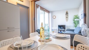 A dining area with a table set for two, a sofa, a TV, and a fan in the background. - Port Arcachon by Interhome (Arcachon)
